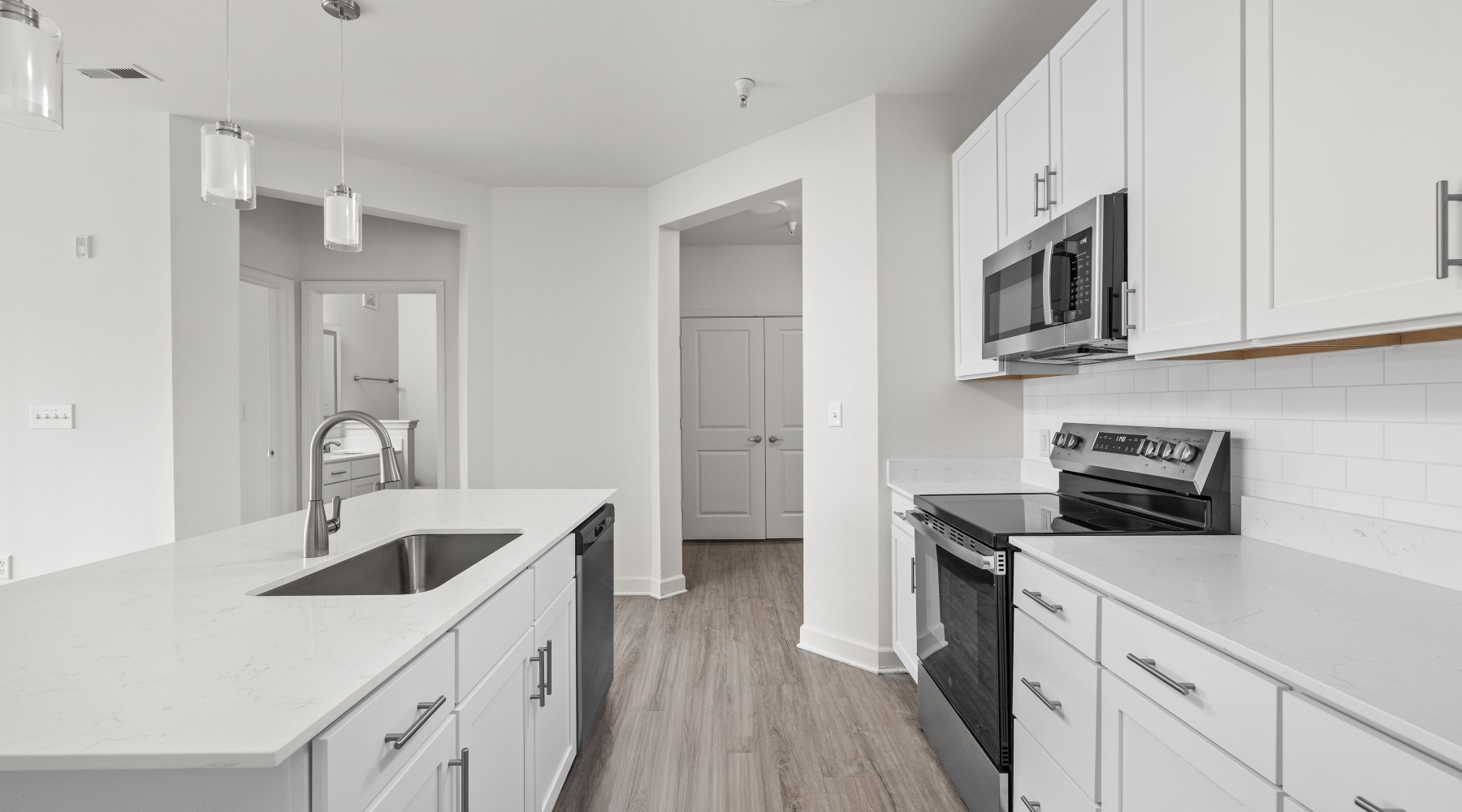 Open concept kitchen with island, quartz countertops, and pendant lighting