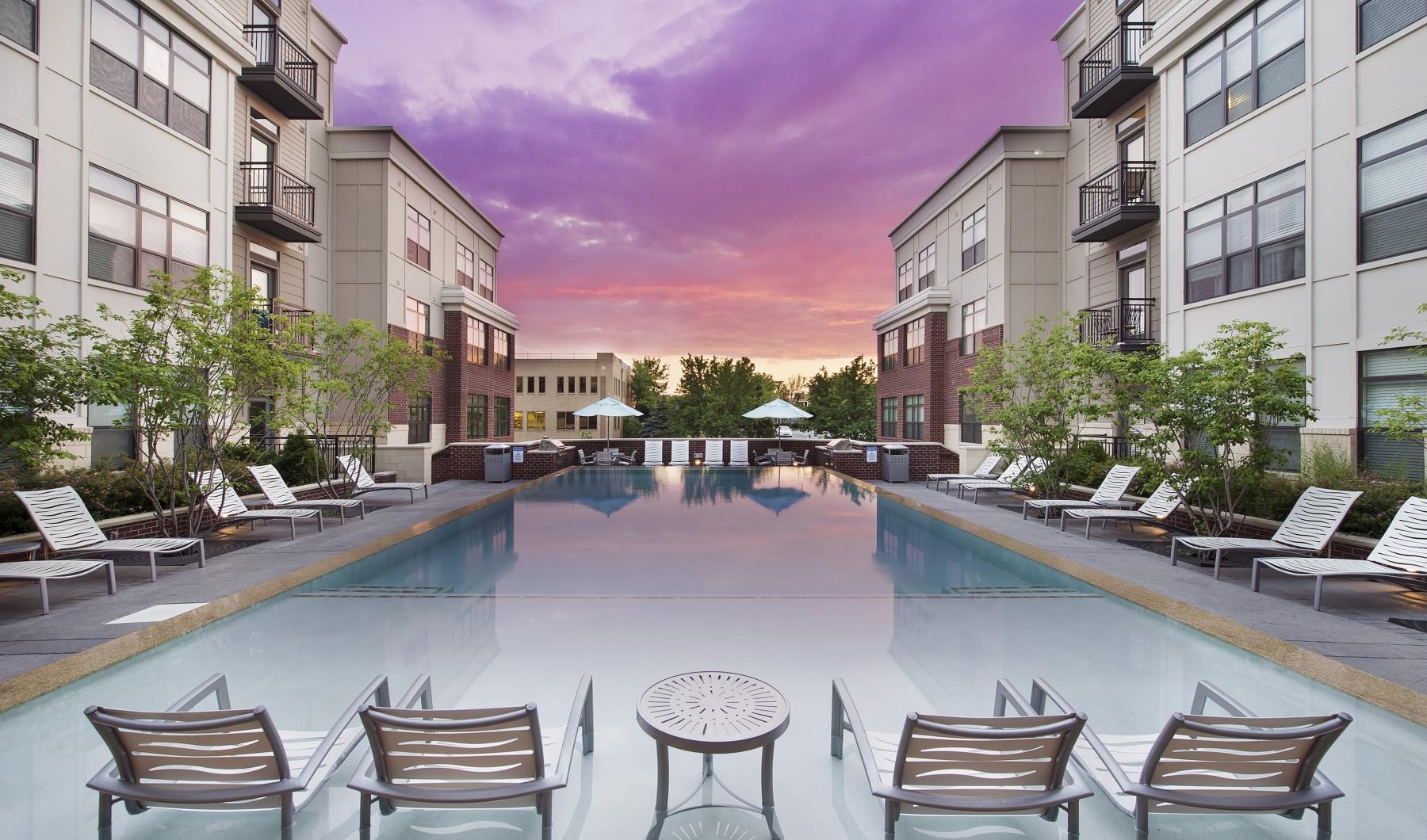a pool with chairs around it in the apartment courtyard