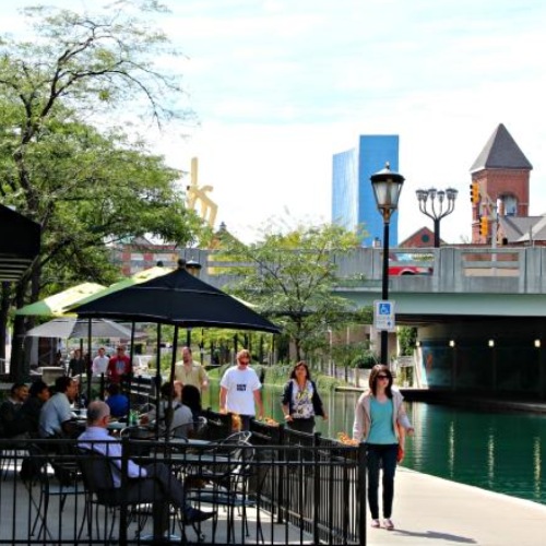 Vibrant community life with a variety of dining options a group of people sitting at tables at a restaurant next to a body of water