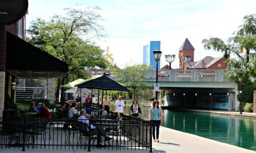 a group of people sitting at tables at a restaurant next to a body of water